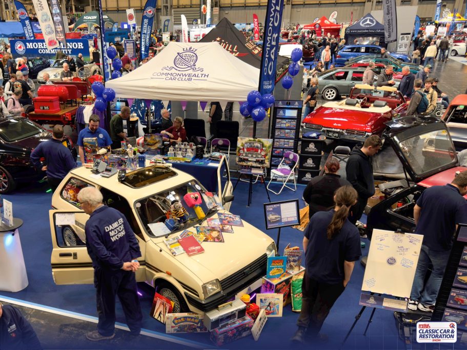 A busy car exhibition featuring various vehicles and vendor displays.